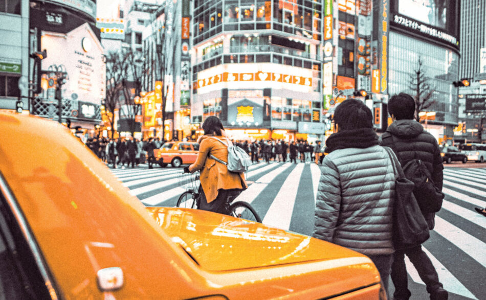 A group of people crossing a street in a city.