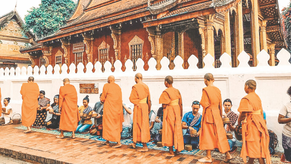 Monks in orange robes standing in front of a building.