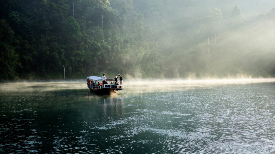 A group of people exploring the most beautiful destinations in Thailand on a boat in a body of water.