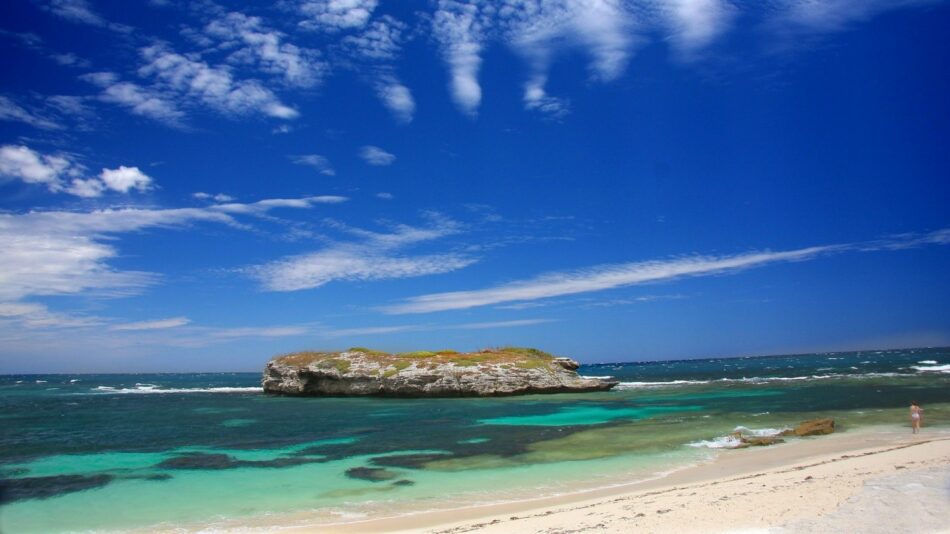 A stunning white sand beach with a mesmerizing blue sky and fluffy clouds, offering incredible photo ops in Australia and New Zealand.