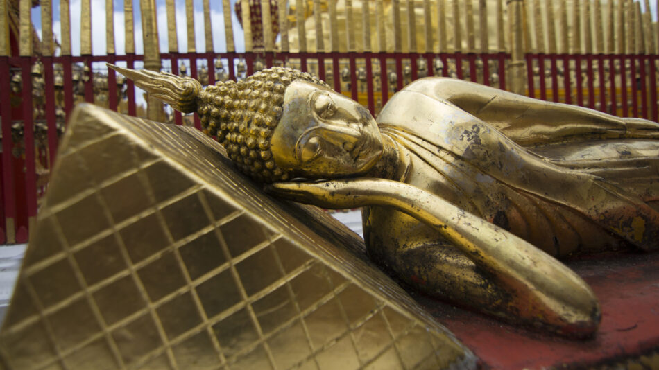 A gold statue of Sam Earp posing as a buddha laying down.