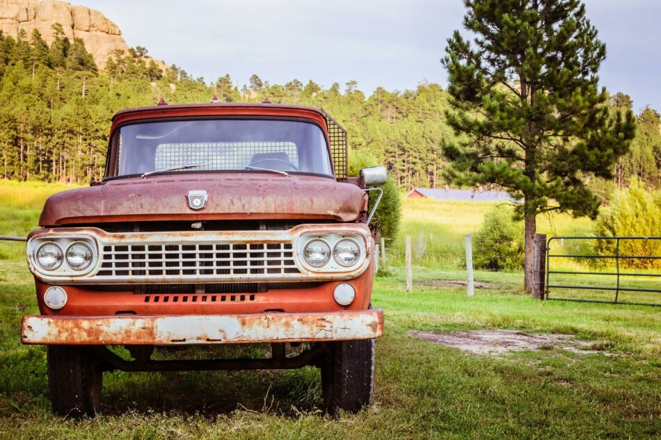 An old rusty truck parked in a grassy field.