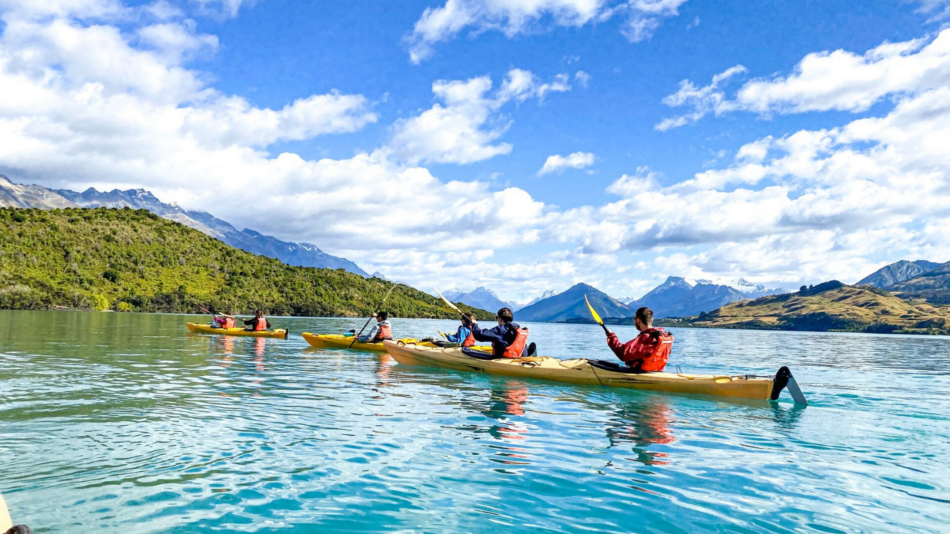 A group of people paddling in kayaks on a lake.