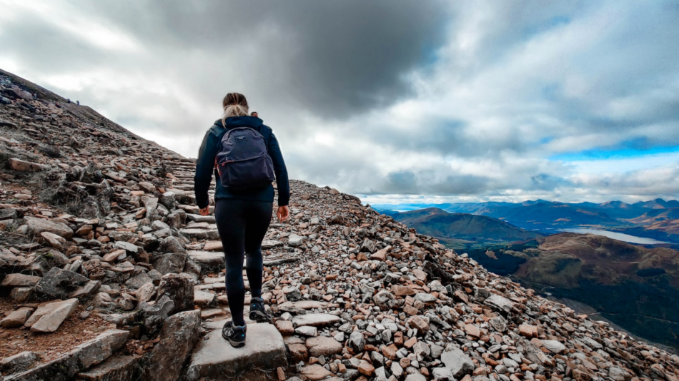 A man is hiking up a mountain with a backpack.