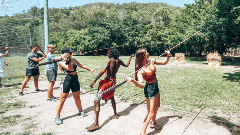 A group of people playing a game of archery in a park.