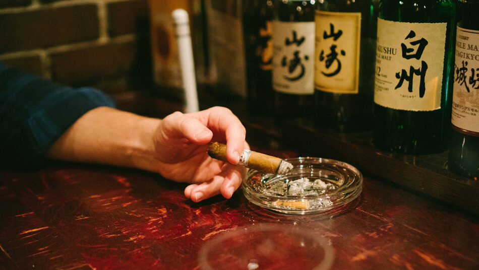 A person smoking a cigarette at a bar.