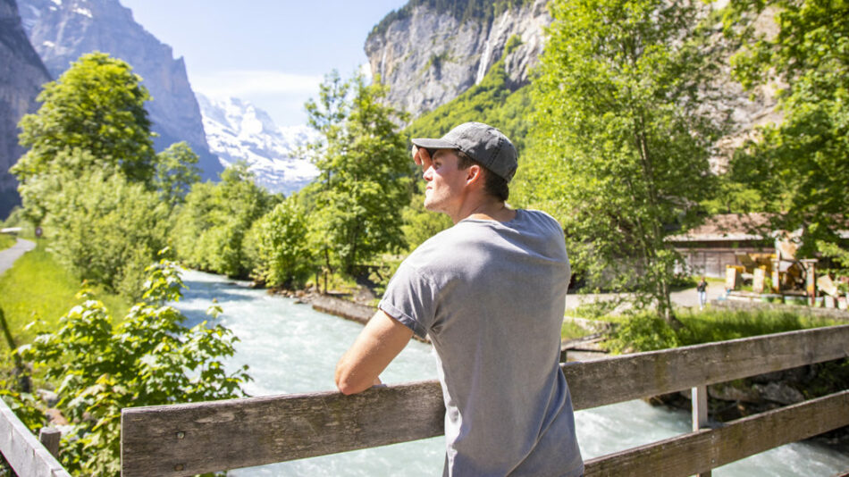 A solo traveler admiring a river in Switzerland.