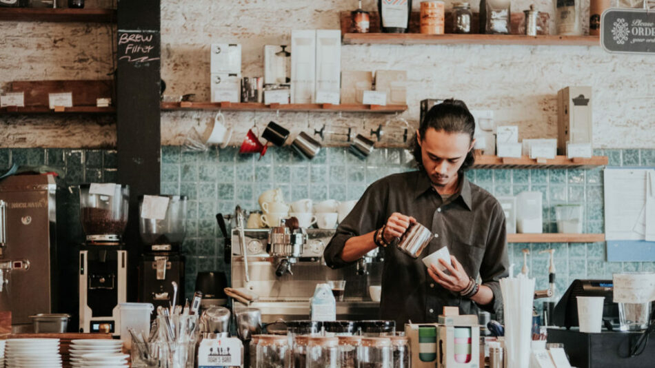 A man pouring coffee in a coffee shop to earn extra money.