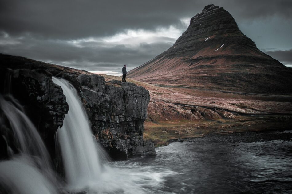 man standing by waterfall in Iceland