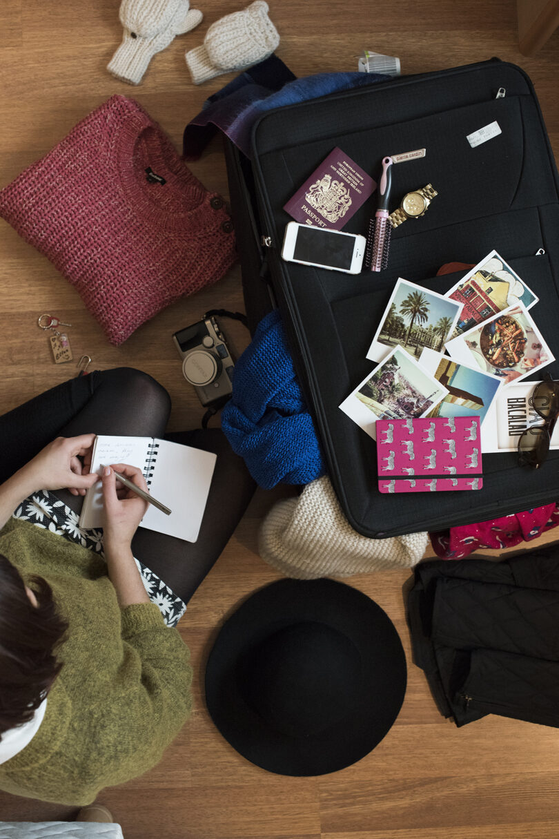 A woman is sitting on the floor with her suitcase, possibly in Africa.