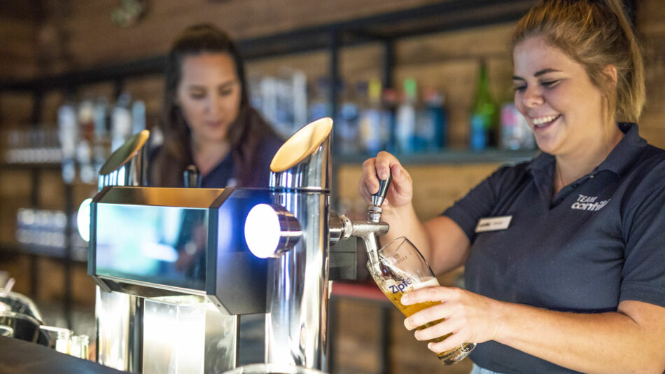 Two women pouring beer at a bar.