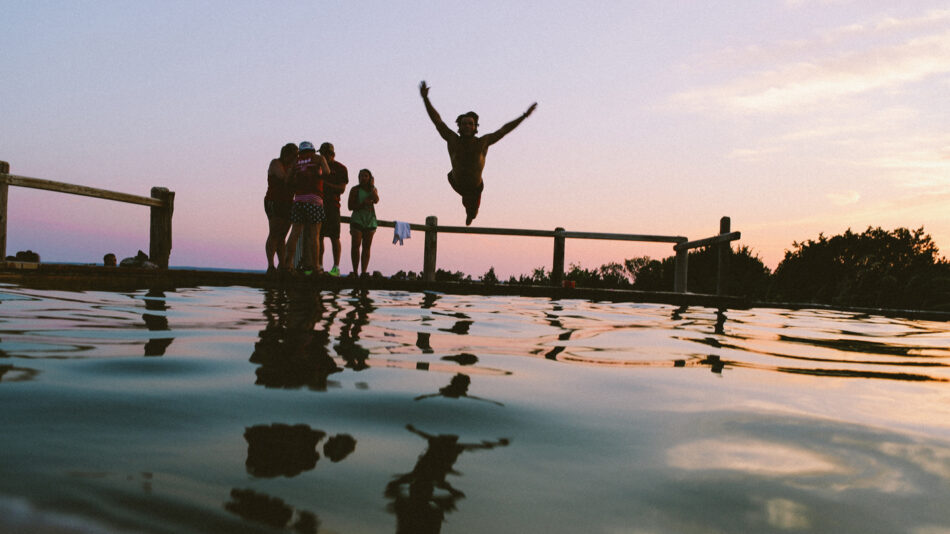 A group of people enjoying a summer evening by jumping into a pool in Europe.