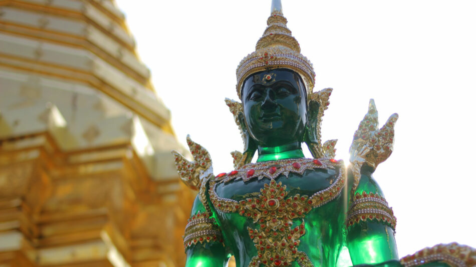 A truly mesmerizing sight, behold a green statue standing proudly in front of a golden building, embodying the charm of one of the most beautiful destinations in Thailand.