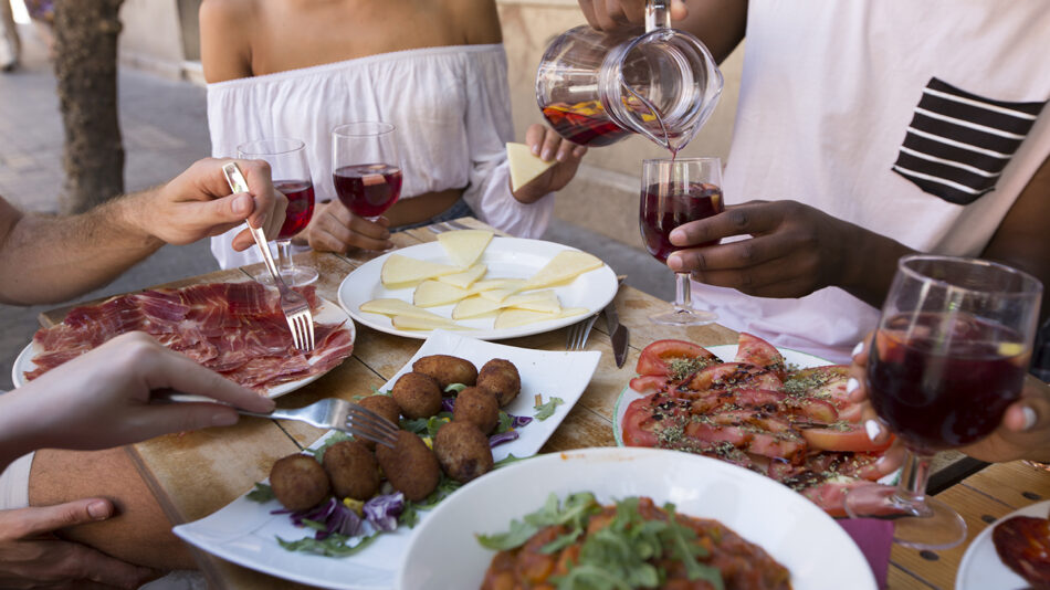 A group of people from diverse European experiences sitting around a table with food.