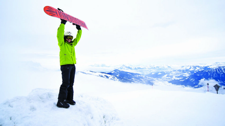 Things to do in Austria: A person holding a snowboard on top of a mountain.