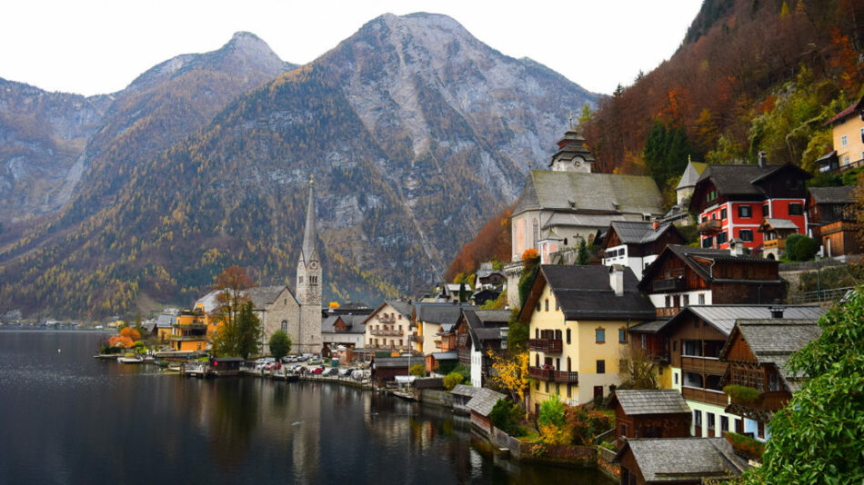 A scenic village in Austria nestled by a lake with picturesque mountains.