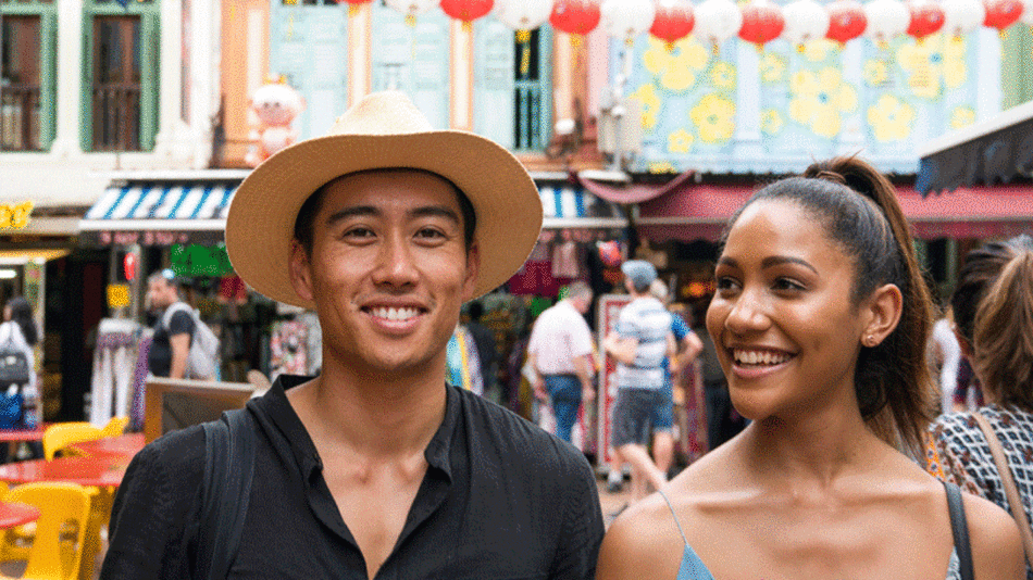 A couple smiling in front of a street in Singapore.