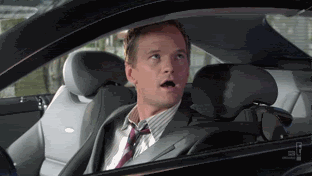 A man in a suit nodding head inside a car.