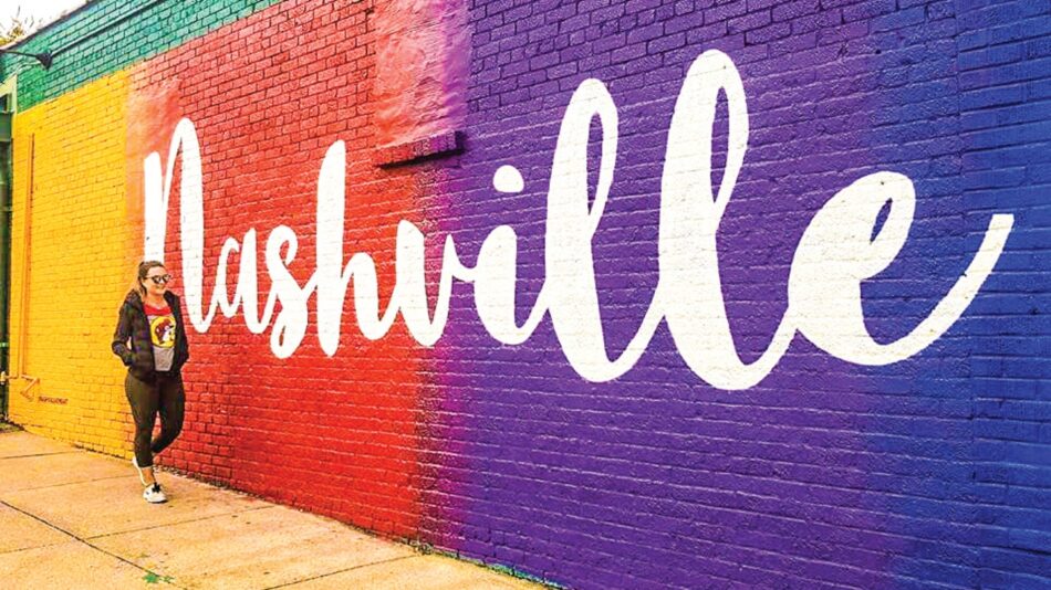 A woman standing in front of a colorful wall with the word nashville written on it.