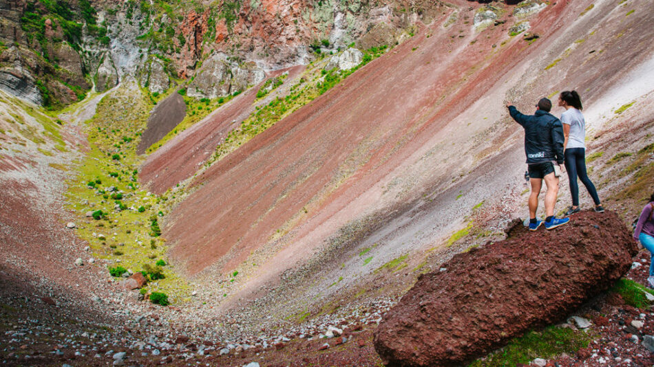 A group of people on a Contiki trip standing on top of a rock in a canyon.