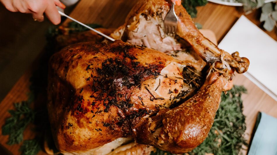 A person is carving a turkey on a table.