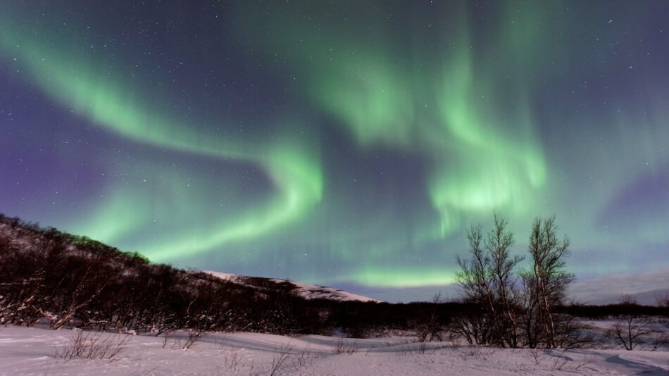 The aurora borealis lights up the sky over an Instagrammable snowy landscape.