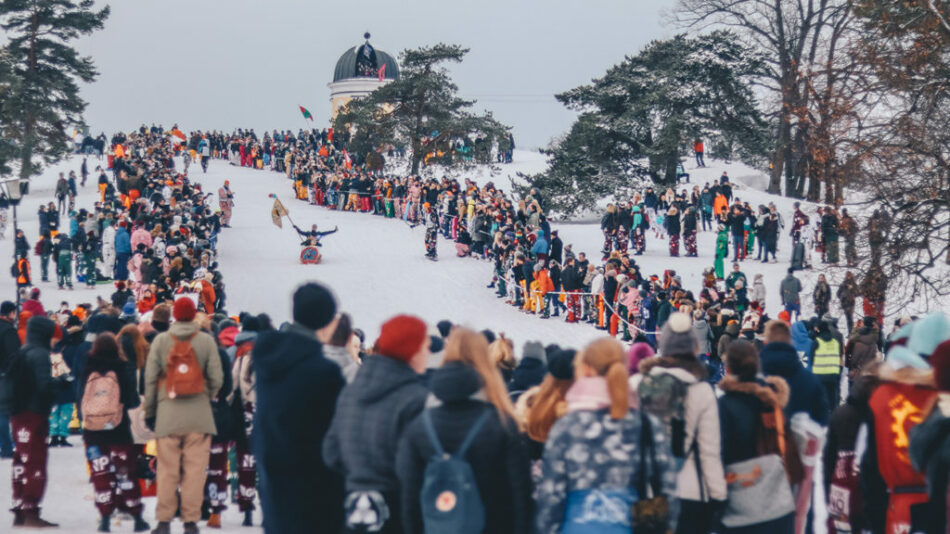 A crowd of people skiing down a snowy hill in Finland.