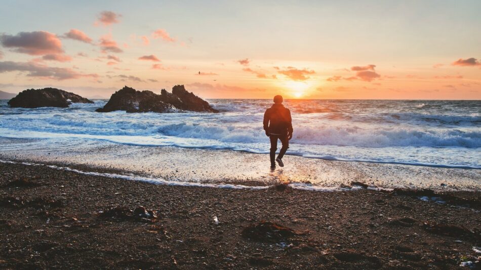 man walking on beach shore in wales