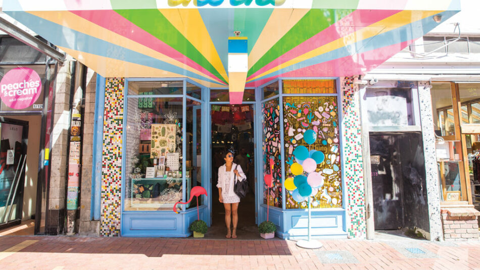 A Contiki Trip Manager is standing in front of a colorful store.