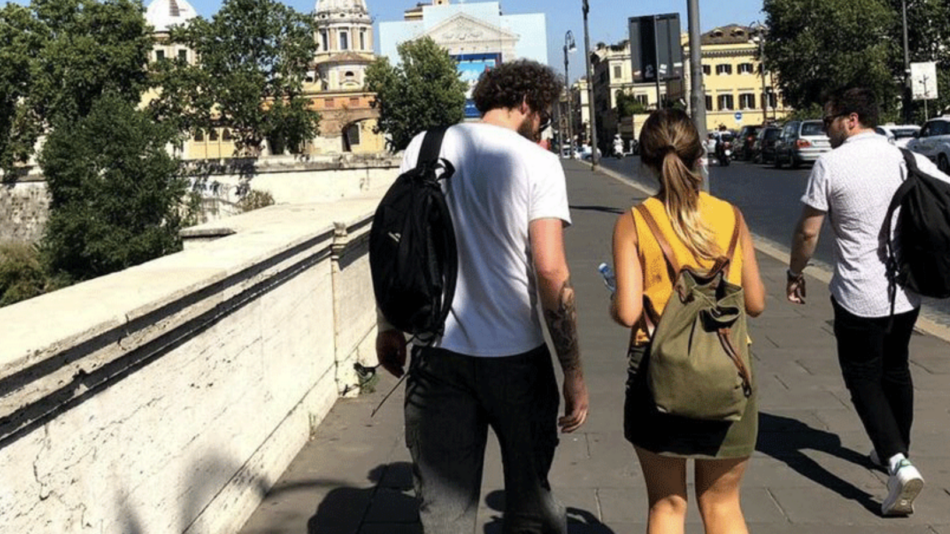 A real travel love story unfolding as a group of people walk down a street in Rome.