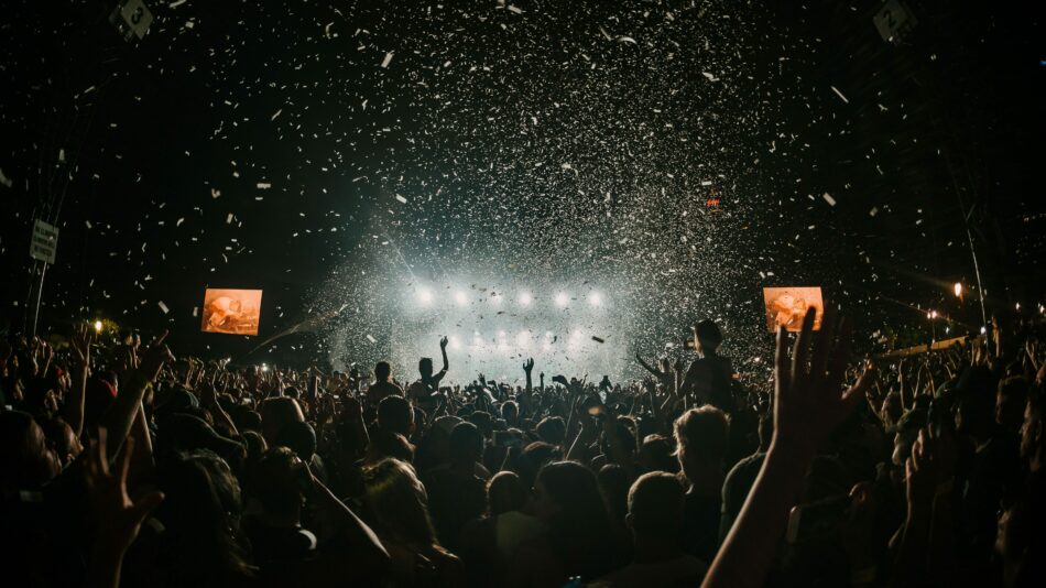 A vibrant crowd at a festival concert with confetti falling from the sky in 2023.