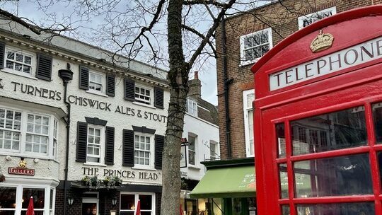 A red telephone booth, one of the Ted Lasso filming locations, in front of a building.