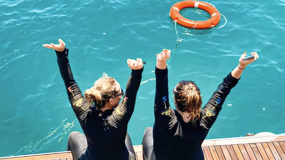 Two women in wetsuits are enjoying an adventurous boat trip in the water.