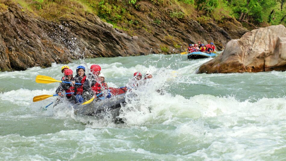 A group of people on an adventure vacation, rafting down rapids in a river.