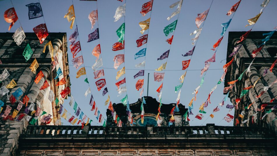 Colorful flags flying in front of a building in Mexico.