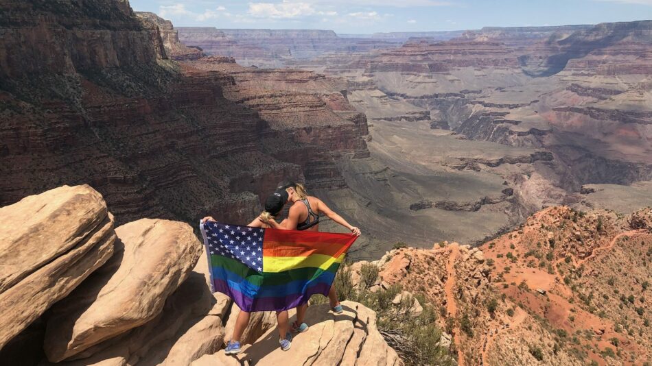 Two Contiki soulmates standing on top of a cliff with a rainbow flag.