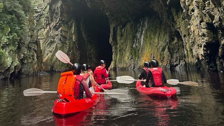 A group of people on a kayaking trip to South Africa, navigating through a cave.