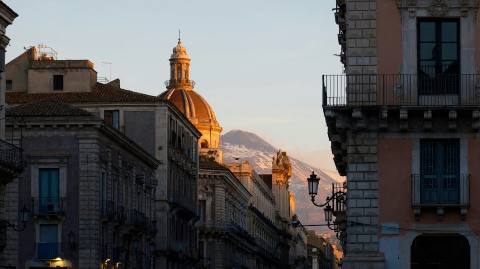 Views of Mount Etna peeking behind buildings in Sicily