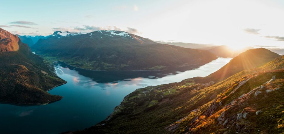 view of Norwegian fjords with hills and snow at sunset