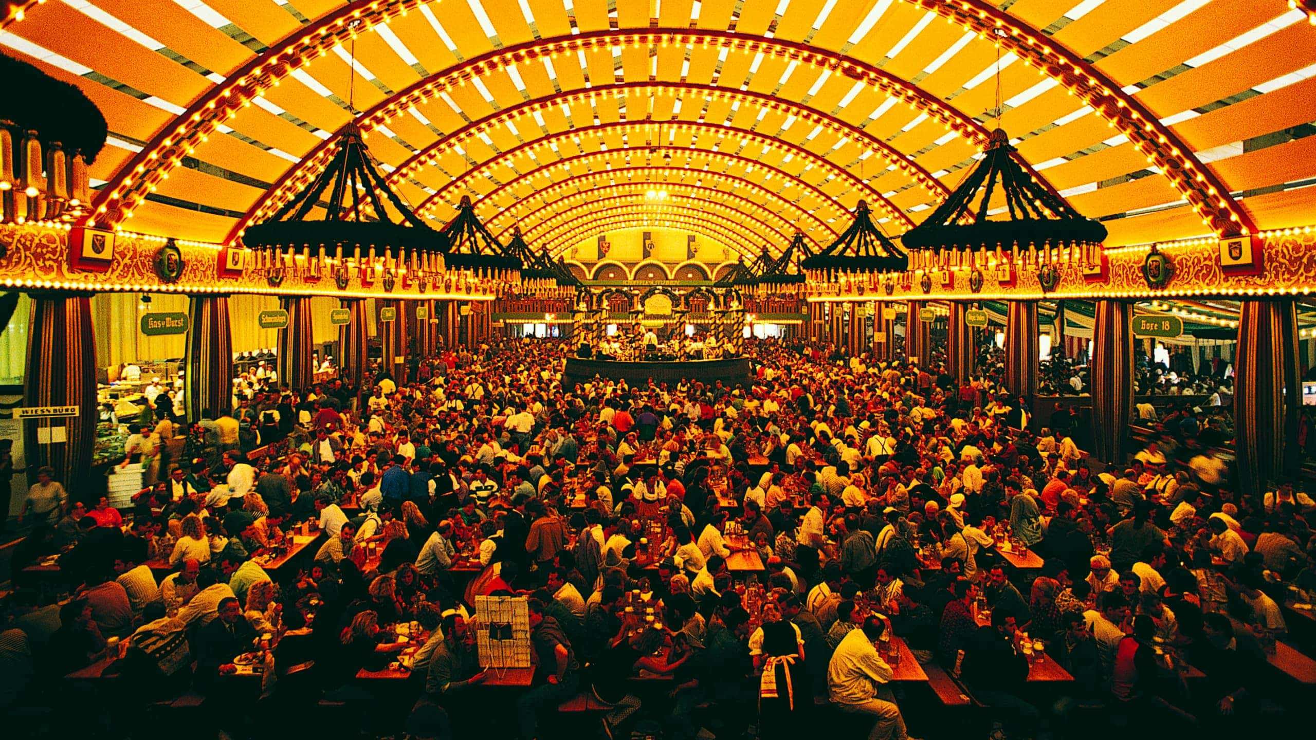 Packed Oktoberfest beer hall tent with ornate vaulted ceiling and thousands of revellers at long wooden tables in Munich Germany - Contiki Oktoberfest Tour