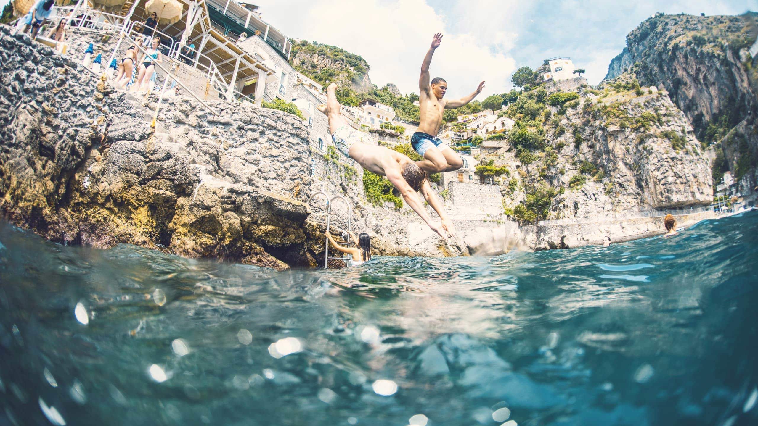 People cliff jumping into the Mediterranean Sea on the Amalfi Coast - Contiki European Quest Tour